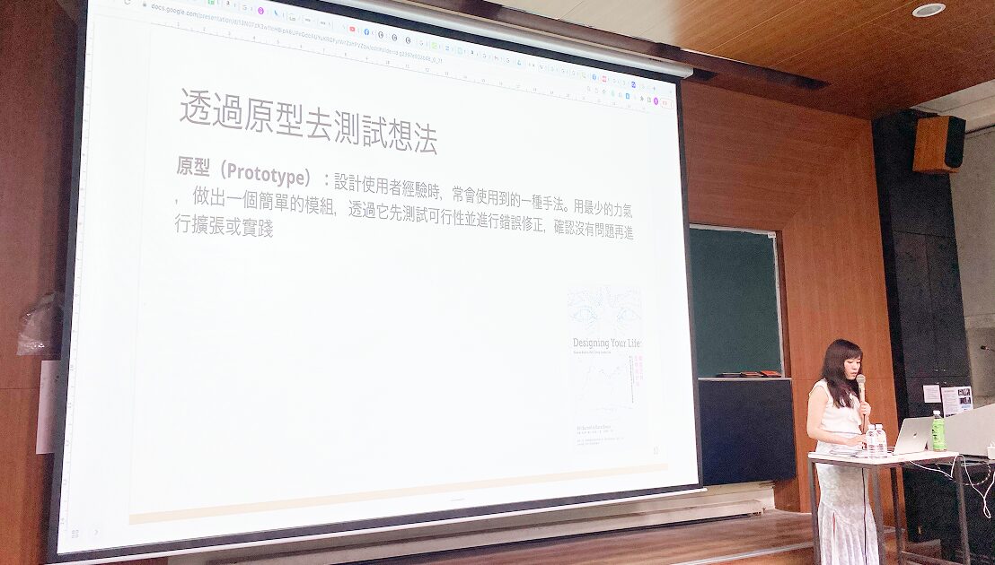 演講現場的側拍，講師正在分享「透過原型去測試想法」的投影片內容